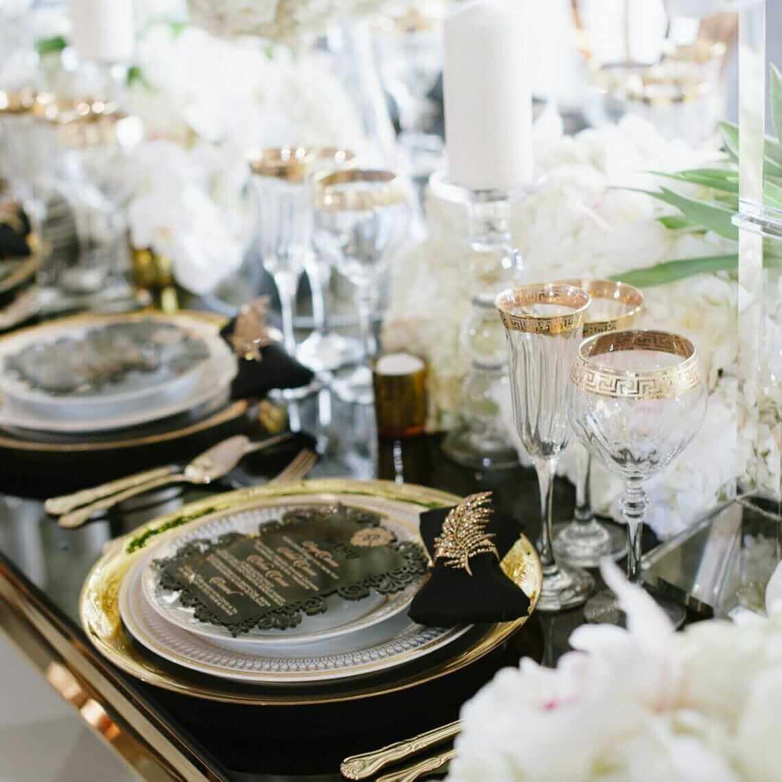 A black and gold table setting with white flowers.