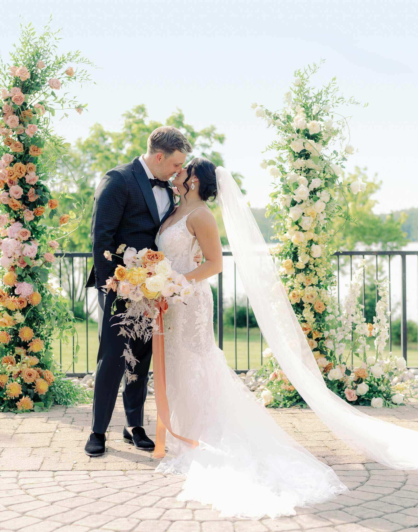 wedding-flowers-ZulTodd-499 A bride and groom kiss in front of a floral arch.